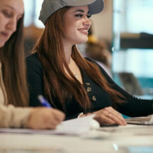 student smiling with friends at computer