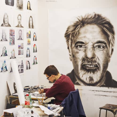 Student working on a fine art project with a large image on the wall behind them