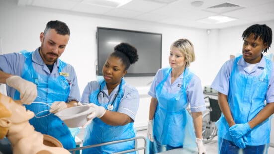 Four Nursing students simulating a medical procedure on a mannequin