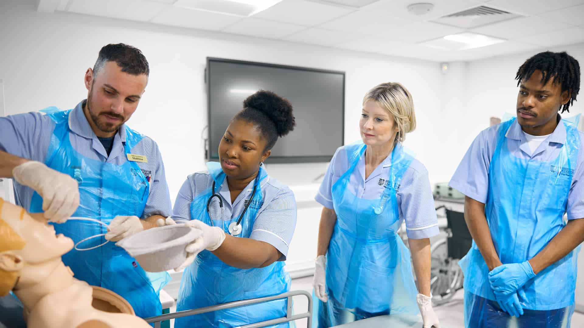 Four Nursing students simulating a medical procedure on a mannequin