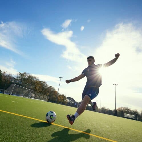 male student kicking a ball