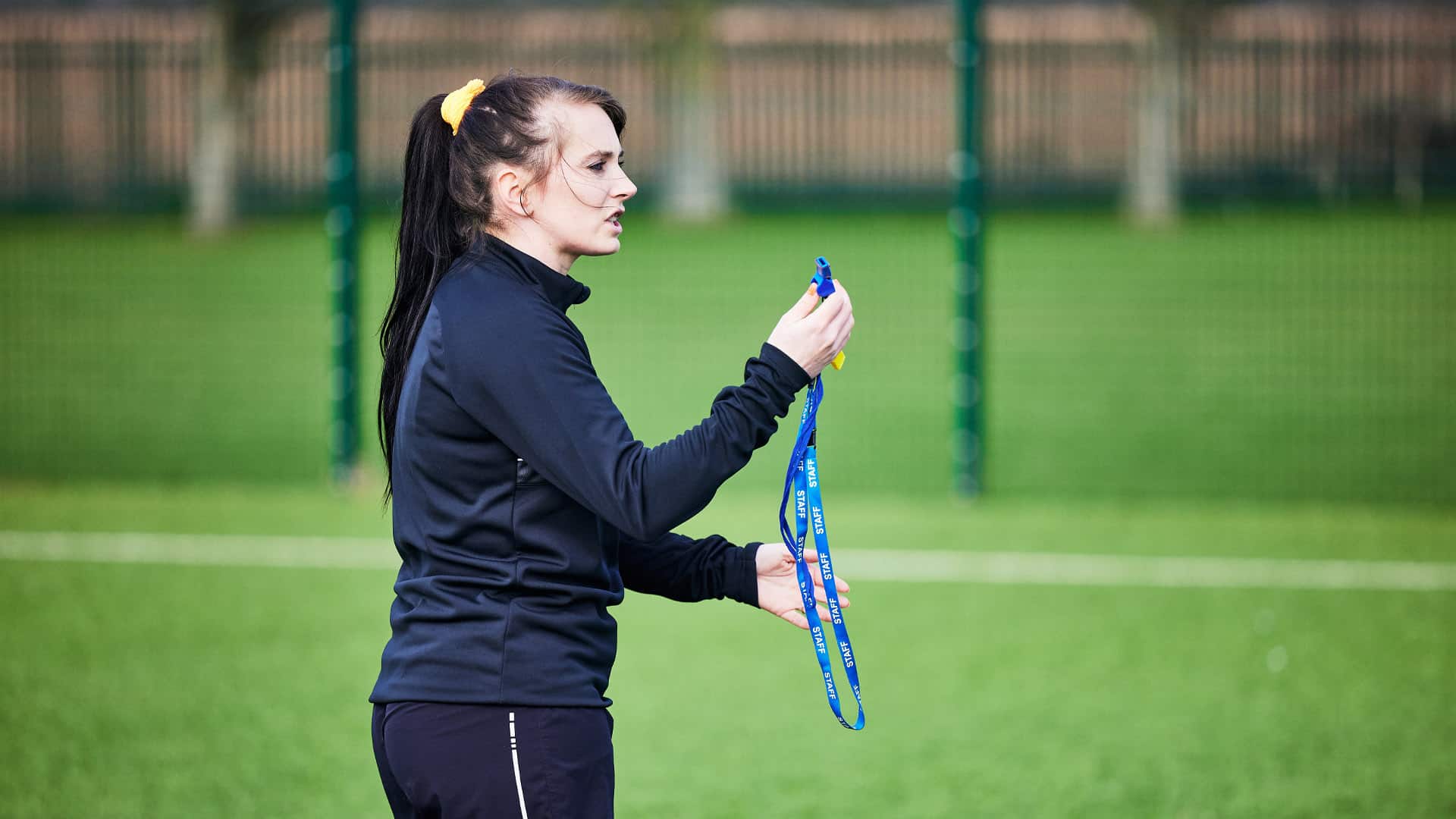 Female football teacher standing with a whistle