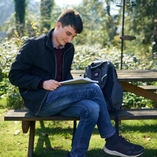 student reading outside on a bench