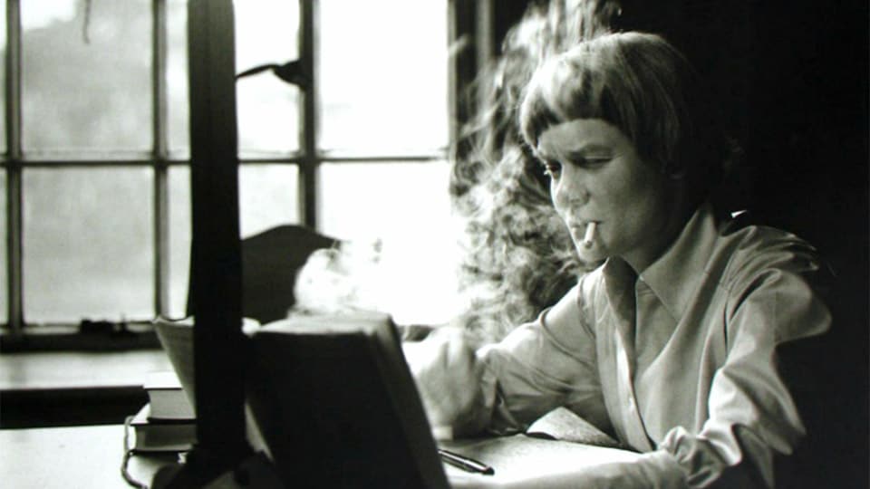 Iris Murdoch writing at her desk in 1958