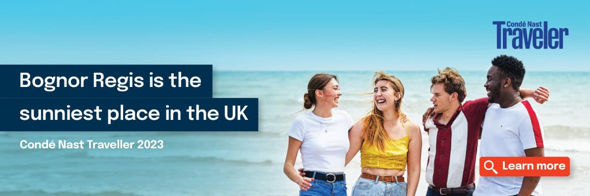 Four students on the beach having a good time. Text that reads 'Bognor Regis is the sunniest place in the UK by Conde Nast Traveller 2023'